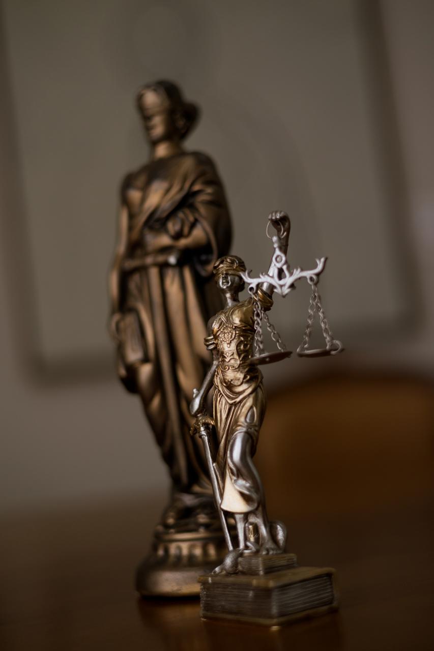 Estatuetas da deusa da Justiça, em tom bronze, sobre a mesa do escritório