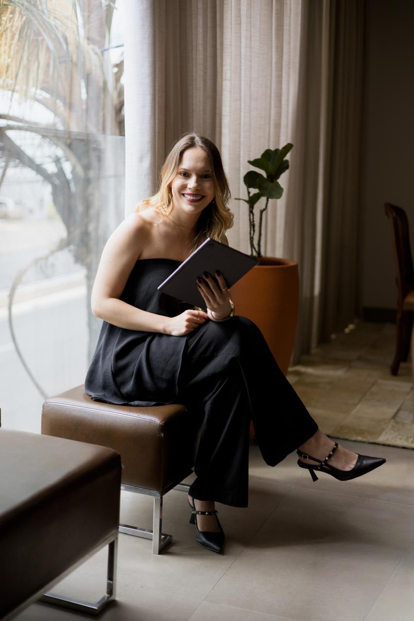 Advogada do escritório sentada junto à janela, segurando um tablet e sorrindo